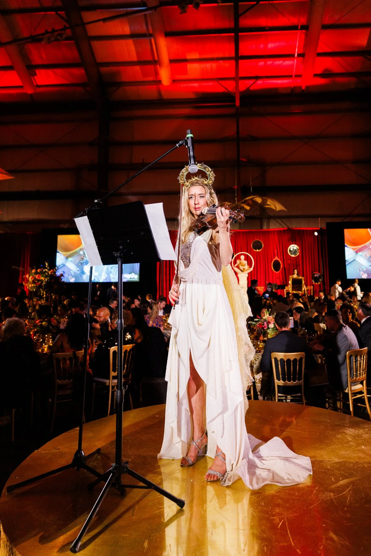 Elin Wolf performing violin onstage at an elegant red-lit gala