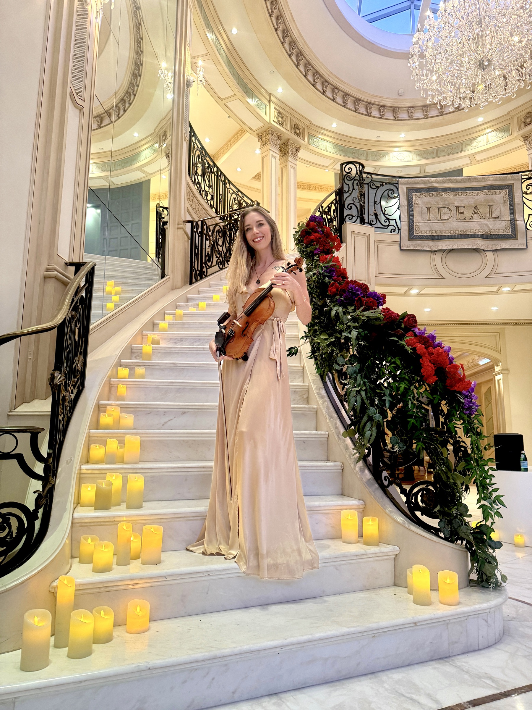 Elin Wolf holding her violin on a candlelit staircase